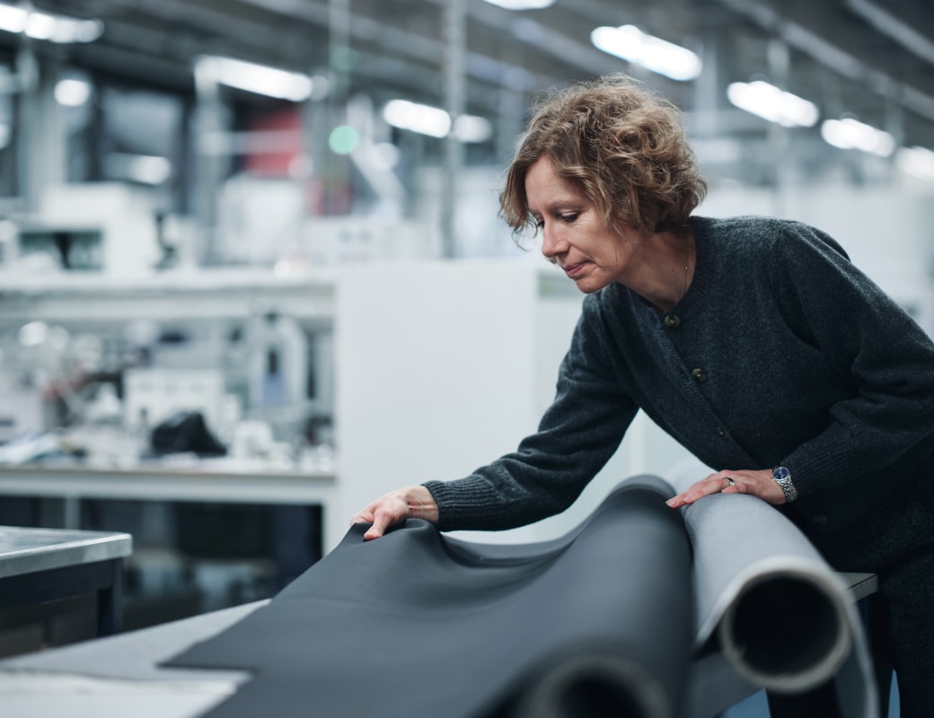 Mulher segurando um tecido de couro em uma fábrica.