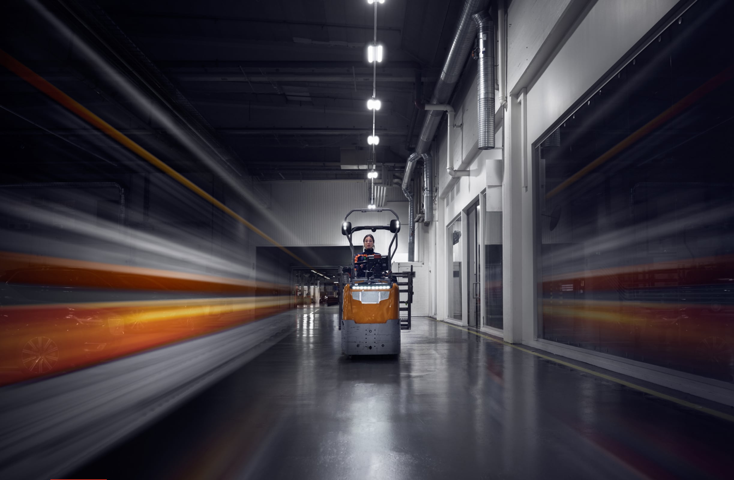 A woman driving a forklift inside a manufacturing plant.