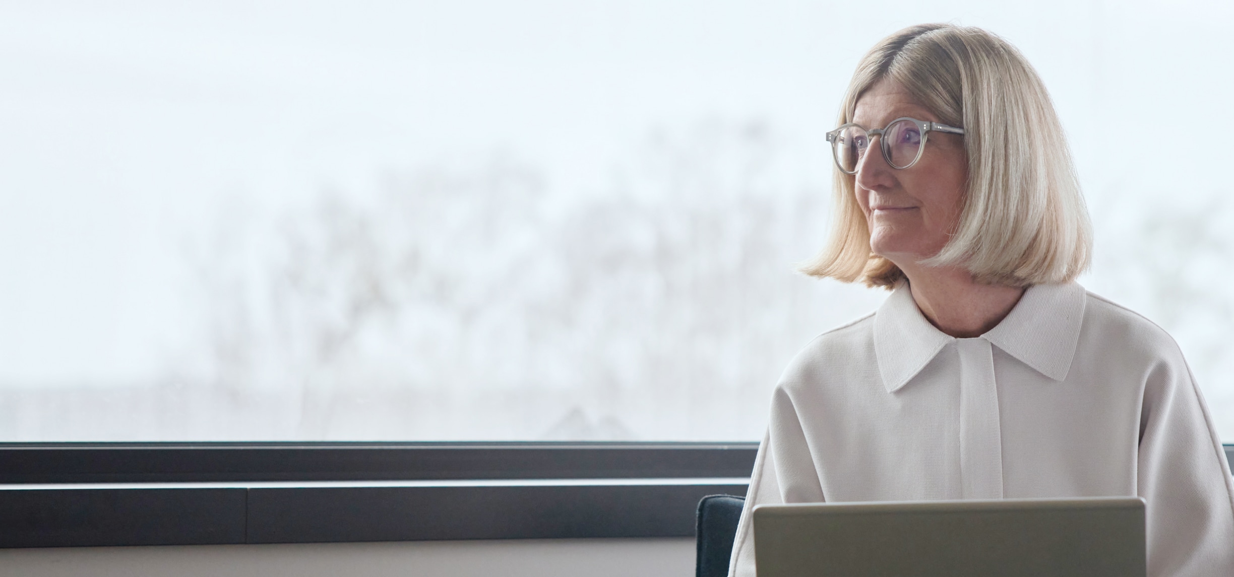 Una anciana con lo que parece una computadora portátil mirando a su derecha.