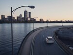 A Volvo driving on a bridge by a river in a city
